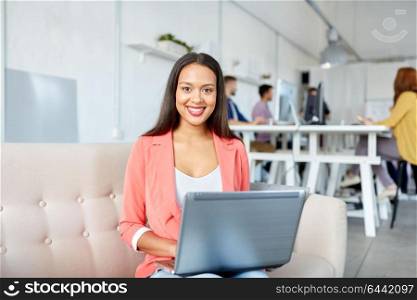 business, education, technology and people concept - happy young african american woman with laptop computer working at office. happy woman with laptop working at office