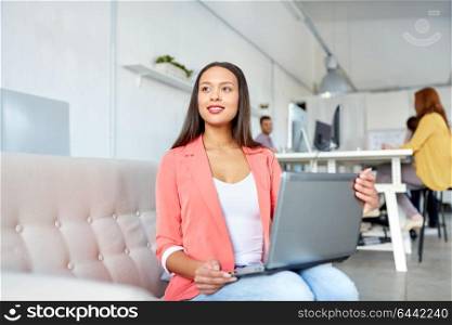 business, education, technology and people concept - happy young african american woman with laptop computer working at office. happy woman with laptop working at office