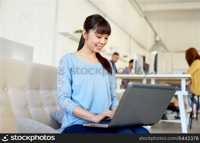 business, education, technology and people concept - happy young asian woman with laptop computer working at office. happy asian woman with laptop working at office