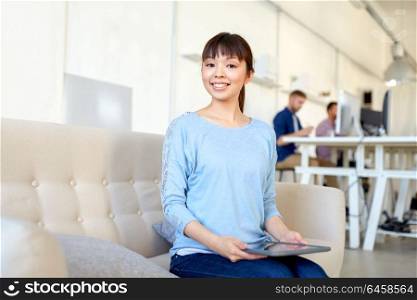 business, education, technology and people concept - happy young asian woman with tablet pc computer working at office. happy asian woman with laptop working at office