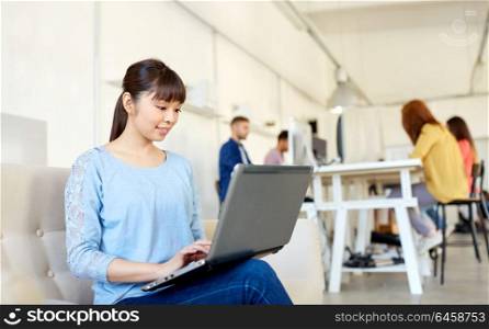 business, education, technology and people concept - happy young asian woman with laptop computer working at office. happy asian woman with laptop working at office