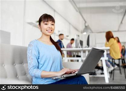 business, education, technology and people concept - happy young asian woman with laptop computer working at office. happy asian woman with laptop working at office. happy asian woman with laptop working at office