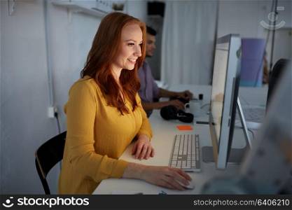 business, education, technology and people concept - happy young woman with computer working at office. happy woman with computer working at office