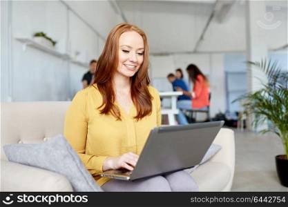 business, education, technology and people concept - happy young woman with laptop computer working at office. happy woman with laptop working at office