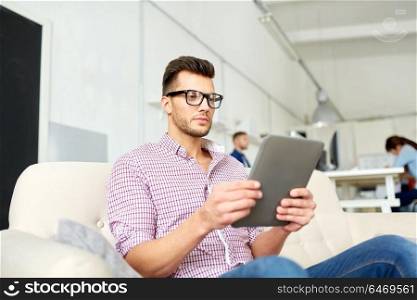 business, education, technology and people concept - man in glasses with tablet pc computer working at office. man in glasses with tablet pc working at office