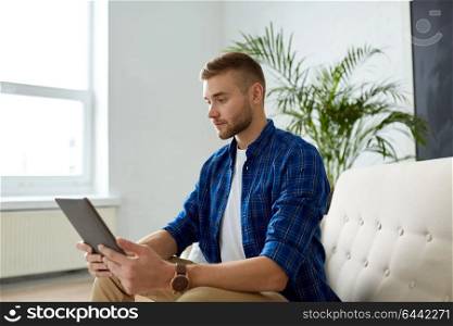 business, education, technology and people concept - man with tablet pc sitting on sofa at office. man with tablet pc sitting on sofa at office