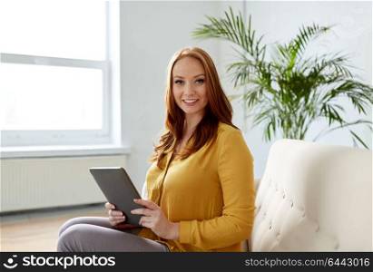 business, education, technology and people concept - smiling young redhead woman with tablet pc computer working at office or home. redhead woman with tablet pc working at office