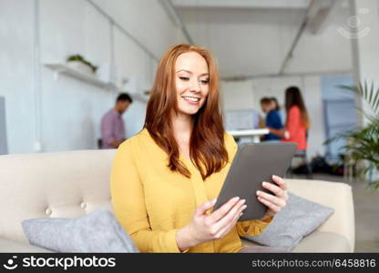 business, education, technology and people concept - smiling young redhead woman with tablet pc computer working at office. redhead woman with tablet pc working at office