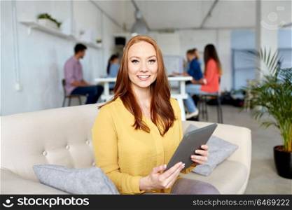 business, education, technology and people concept - smiling young redhead woman with tablet pc computer working at office. redhead woman with tablet pc working at office