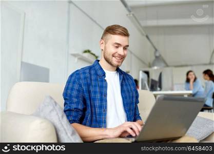 business, education, technology and people concept - young man with laptop computer working at office. man with laptop working at office