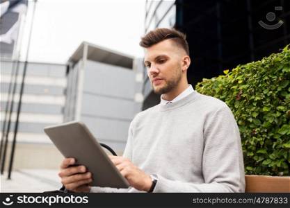 business, education, technology, communication and people concept - creative man with tablet pc computer sitting on city street bench