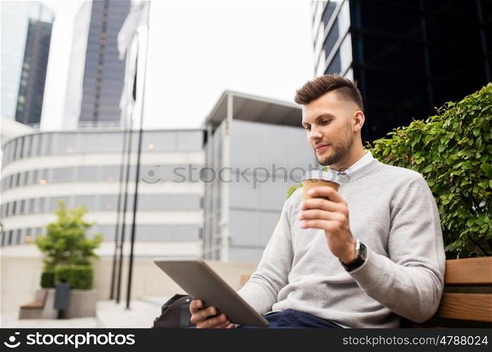 business, education, technology, communication and people concept - creative man with tablet pc computer drinking coffee from paper cup and sitting on city street bench