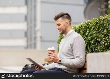 business, education, technology, communication and people concept - creative man with tablet pc computer drinking coffee from paper cup and sitting on city street bench. man with tablet pc and coffee on city street bench