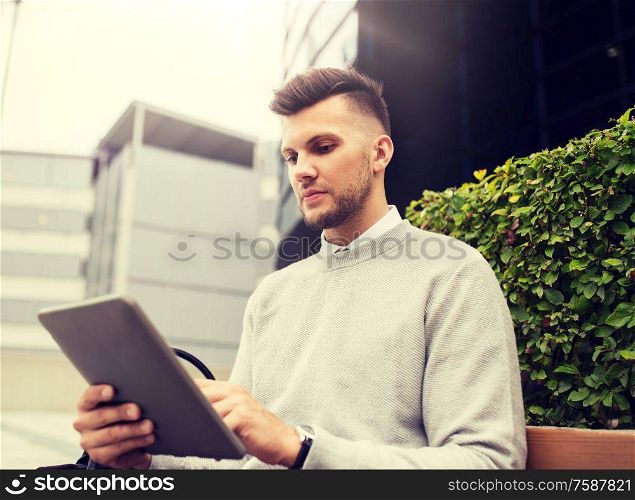 business, education, technology, communication and people concept - creative man with tablet pc computer sitting on city street bench. man with tablet pc sitting on city street bench