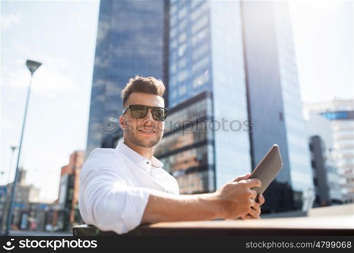 business, education, technology, communication and people concept - happy smiling man in sunglasses with tablet pc computer sitting on city street bench