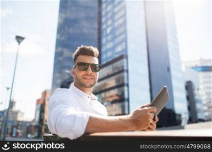 business, education, technology, communication and people concept - happy smiling man in sunglasses with tablet pc computer sitting on city street bench