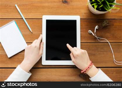 business, education, technology, people and advertisement concept - close up of woman with blank tablet pc computer screen on wooden table
