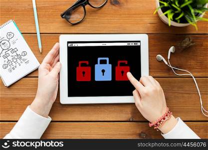 business, education, technology, people and cyber protection concept - close up of woman with lock icon on tablet pc computer screen on wooden table