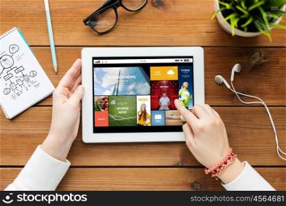 business, education, technology, people and mass media concept - close up of woman with internet news application on tablet pc computer screen on wooden table