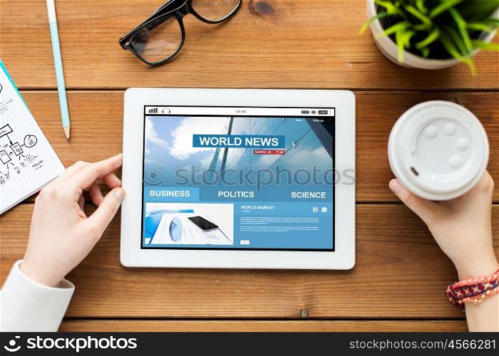 business, education, technology, people and mass media concept - close up of woman with world news on tablet pc computer screen and coffee on wooden table