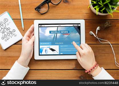business, education, technology, people and mass media concept - close up of woman with world news on tablet pc computer screen on wooden table