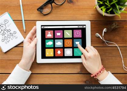 business, education, technology, people and multimedia concept - close up of woman with menu icons on tablet pc computer screen on wooden table