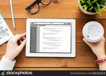 business, education, technology, people and programming concept - close up of woman with coding on tablet pc computer screen and coffee on wooden table