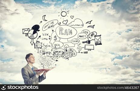 Business education. Young businessman with opened book in hands and business sketches