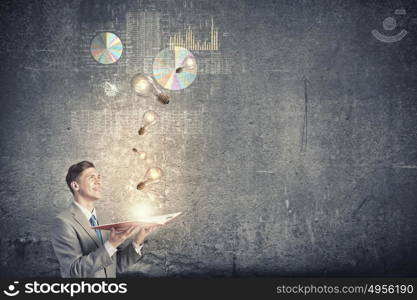 Business education. Young businessman with opened book in hands blowing on pages