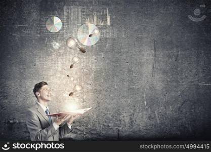 Business education. Young businessman with opened book in hands blowing on pages