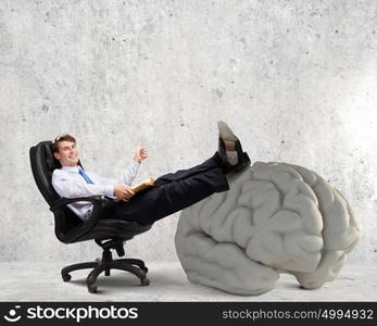 Business education. Young handsome businessman sitting in chair and reading book