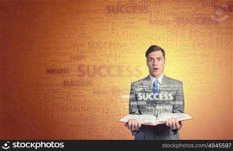 Business education. Young shocked businessman with opened book in hands