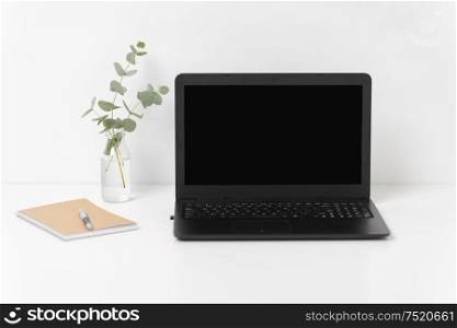 business, electronics and interior concept - laptop with black screen on white office table. laptop with black screen on white office table