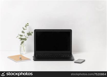 business, electronics and interior concept - laptop with black screen on white office table. laptop with black screen on white office table