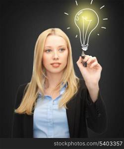 business, energy and environment concept - woman drawing light bulb on the virtual screen