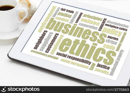 business ethics word cloud on a digital tablet with a cup of coffee