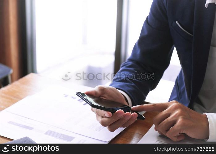 business executive auditor using moblie smart phone for data report investment.