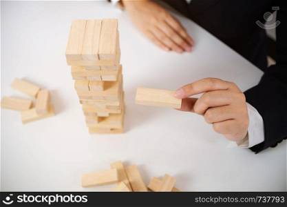 Business executive holding wooden block, Risk and strategy in planing.