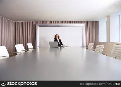 Business Executive Sitting in Boardroom with Laptop