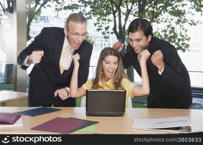 Business executives looking excited in front of a laptop