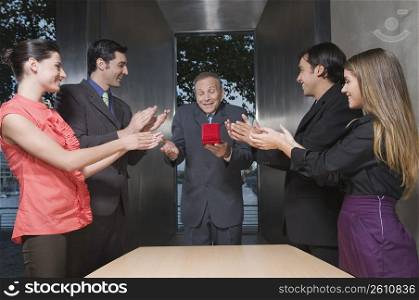 Business executives presenting a gift to their colleague in an office