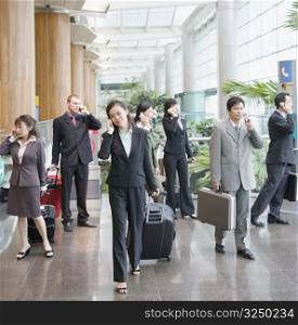 Business executives talking on mobile phones and leaving an airport lounge