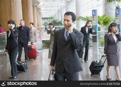 Business executives talking on mobile phones and leaving an airport lounge