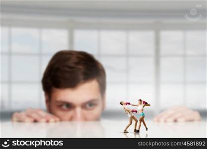 Business fight as competion concept. Young woman looking from under table on fighting people