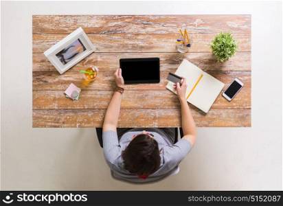 business, finance and technology concept - woman with tablet pc and credit card at table. woman with tablet pc and credit card at table