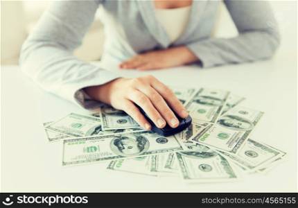 business, finance, internet earning and people concept - close up of woman hand with computer mouse on money