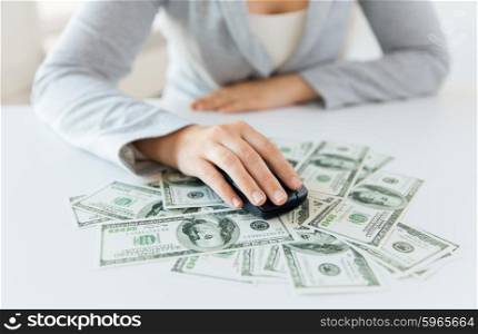 business, finance, internet earning and people concept - close up of woman hand with computer mouse on money