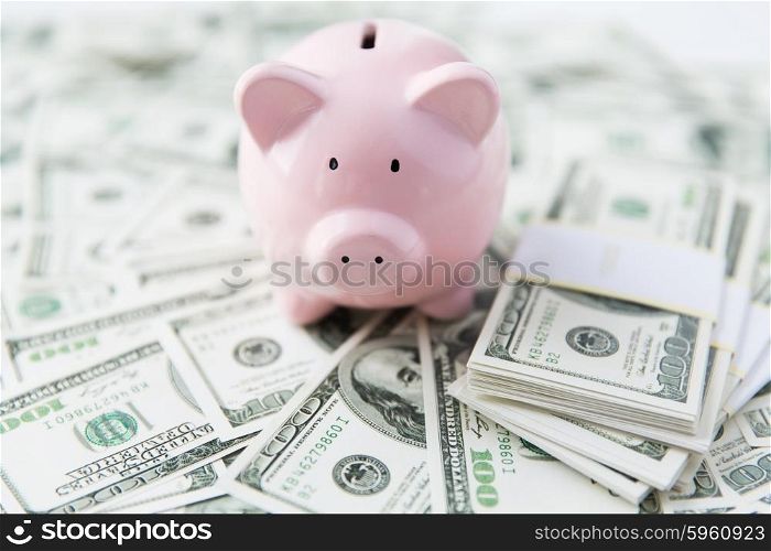 business, finance, investment, saving and corruption concept - close up of dollar cash money and piggy bank on table