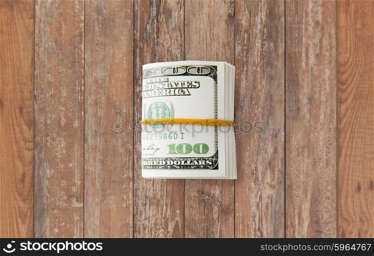business, finance, investment, saving and corruption concept - close up of dollar money packet tied with rubber on wooden table
