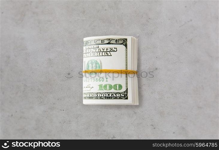 business, finance, investment, saving and corruption concept - close up of dollar money packet tied with rubber on gray concrete table